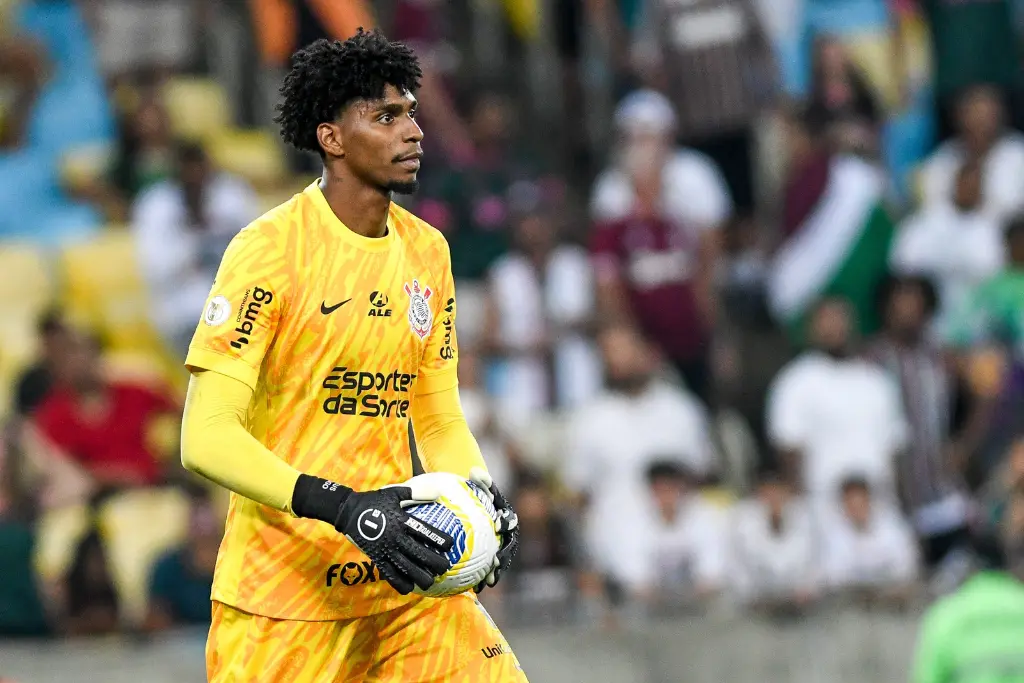 Goleiro Hugo Souza, um dos destaques entre os jogadores do Corinthians na Seleção, veste o uniforme amarelo de goleiro do Timão enquanto segura a bola durante uma partida oficial.