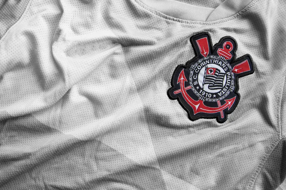 Camisa branca do Corinthians com tecido texturizado e escudo do clube bordado em destaque.
