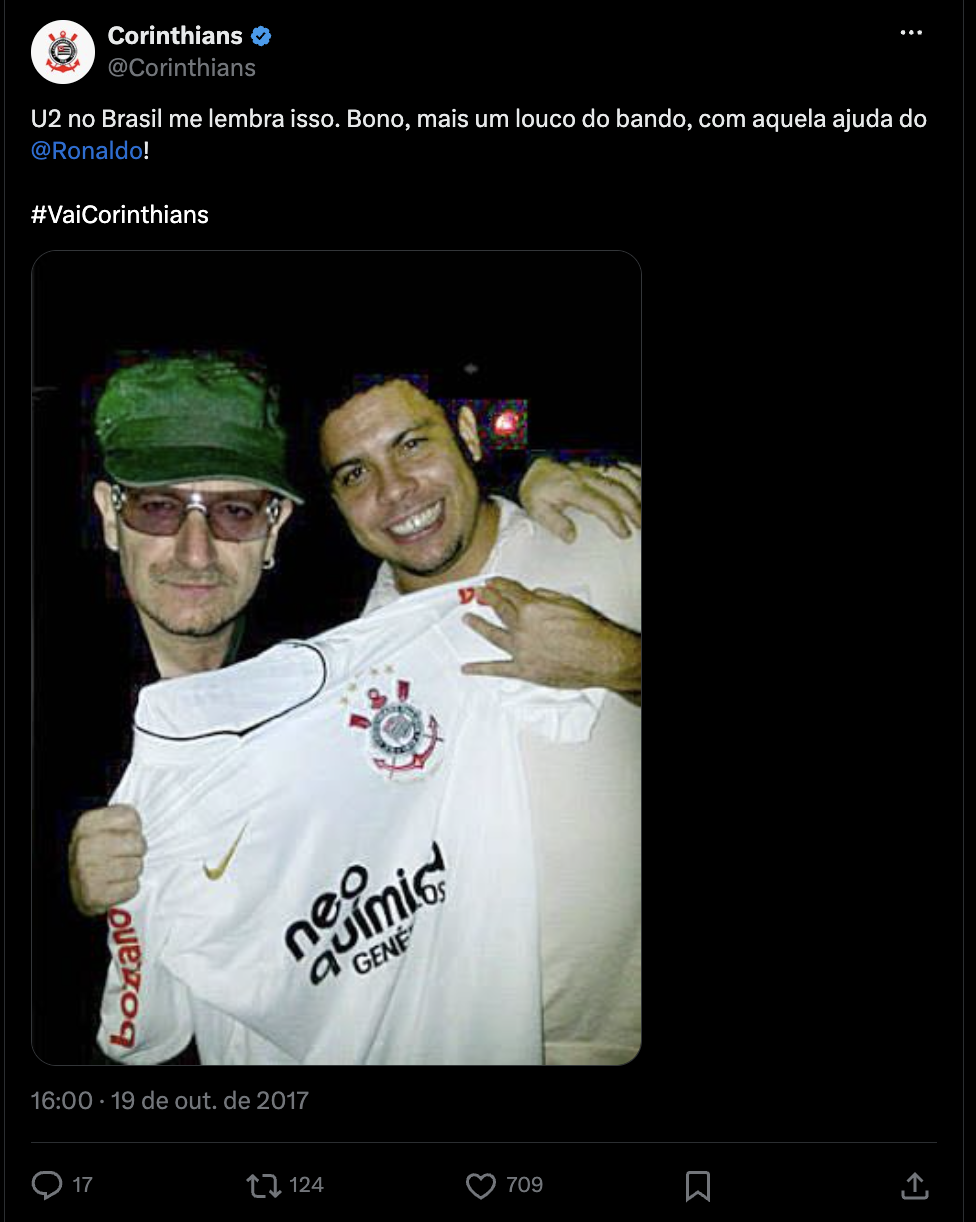 Captura de tela de post de 2017 da conta do Corinthians no Twitter, que exibe uma foto de Bono Vox exibindo uma camisa do Corinthians, junto com Ronaldo Fenômeno.